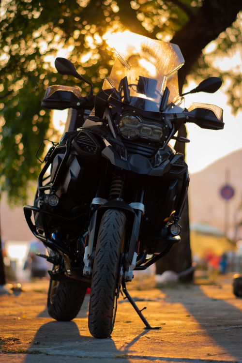 Free Dynamic view of a touring motorcycle with lush backdrop at sunset, exuding adventure vibes. Stock Photo