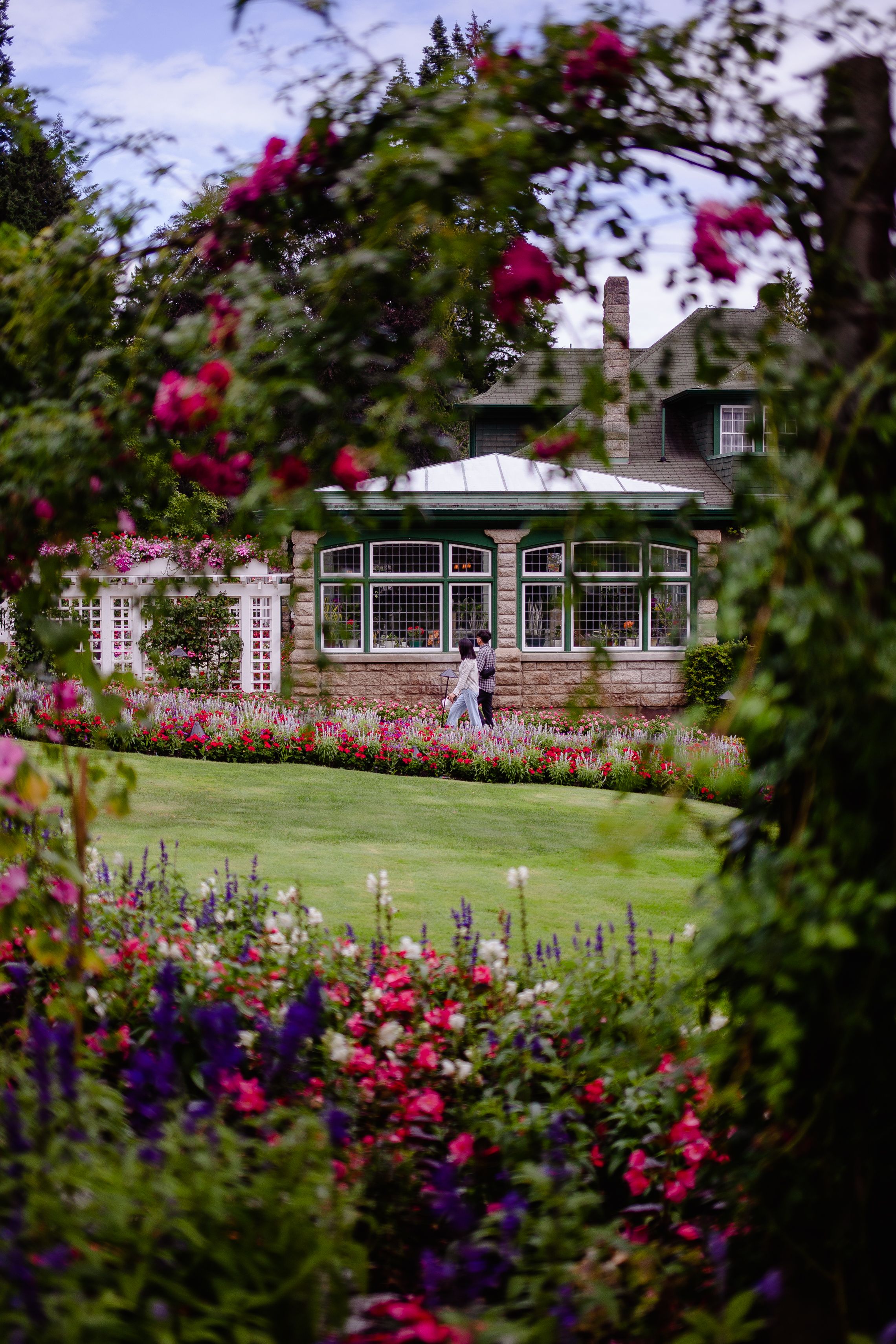 Victorian house surrounded by vibrant garden with couple walking by - neighborhood history for realtors