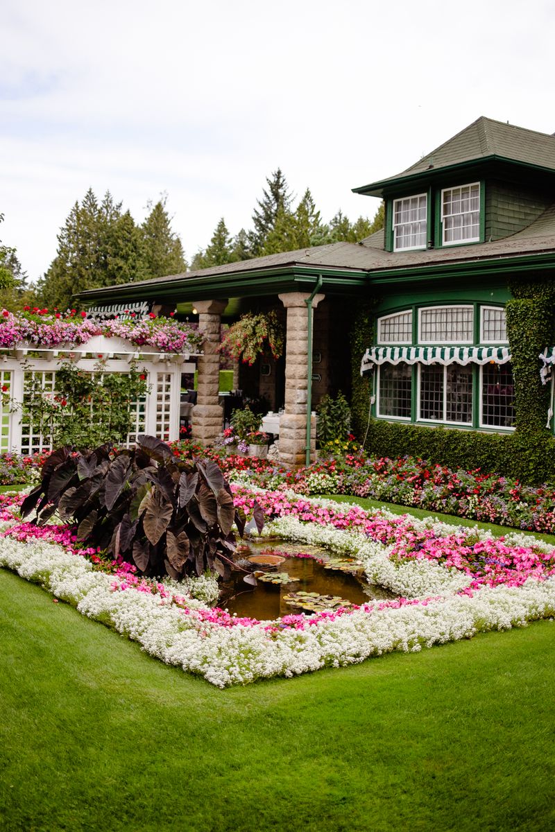 Vibrant flowerbeds in front of a classic green house