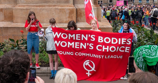 Women's rights protest with a 'Women's Bodies, Women's Choice' banner at a crowded rally.
