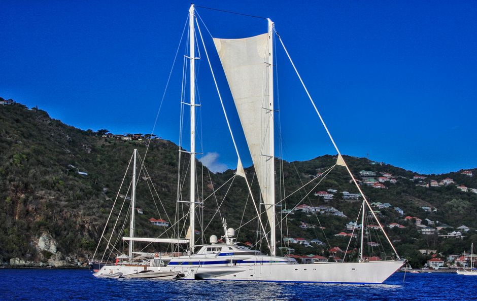 Amazing Experience the British Virgin Islands through an Unforgettable Tour Review 2026 - A luxury yacht sails in crystal clear waters near a scenic, hilly coastline under a vivid blue sky.