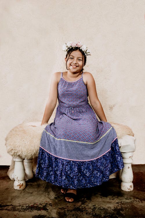 Smiling Girl in a Flower Crown and a Dress Sitting on a Bench