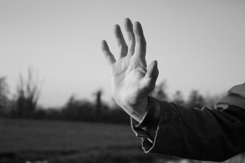 Free Monochrome close-up of a hand raised against a blurred outdoor background. Stock Photo