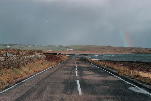 Free Beautiful view of a coastal road in Keil, Scotland with a rainbow over the sea. Stock Photo