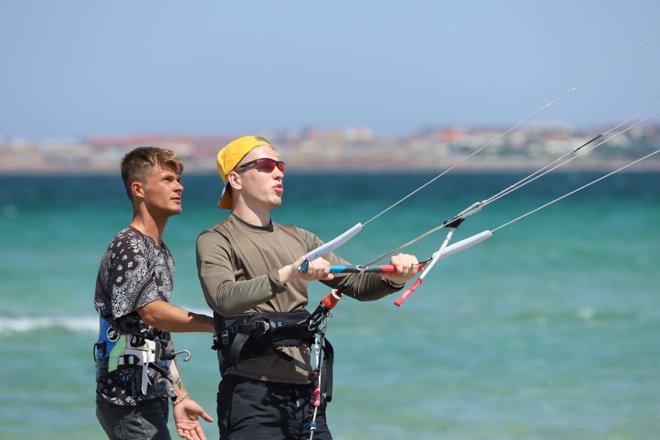 Two men learning kiteboarding on a bright summer day by the sea.