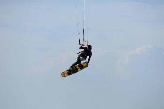 Thrilling windsurfing action in mid-air captured against a clear sky, showcasing skill and adventure.