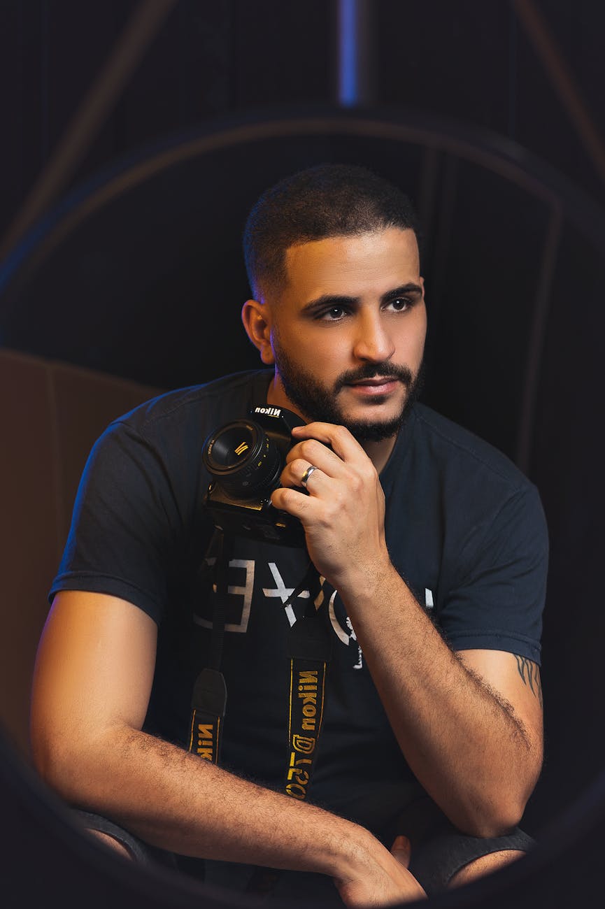 A young man holding a camera indoors, showcasing the art of photography.
