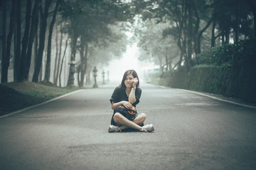 Fille Assise Sur Une Route En Béton Gris