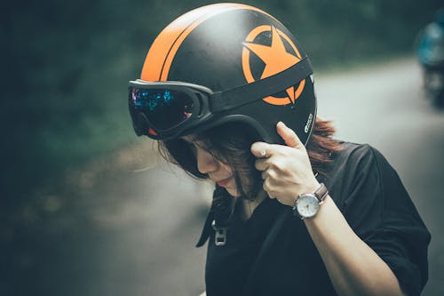 女人穿著黑色襯衫和黑色和橙色的半臉頭盔
