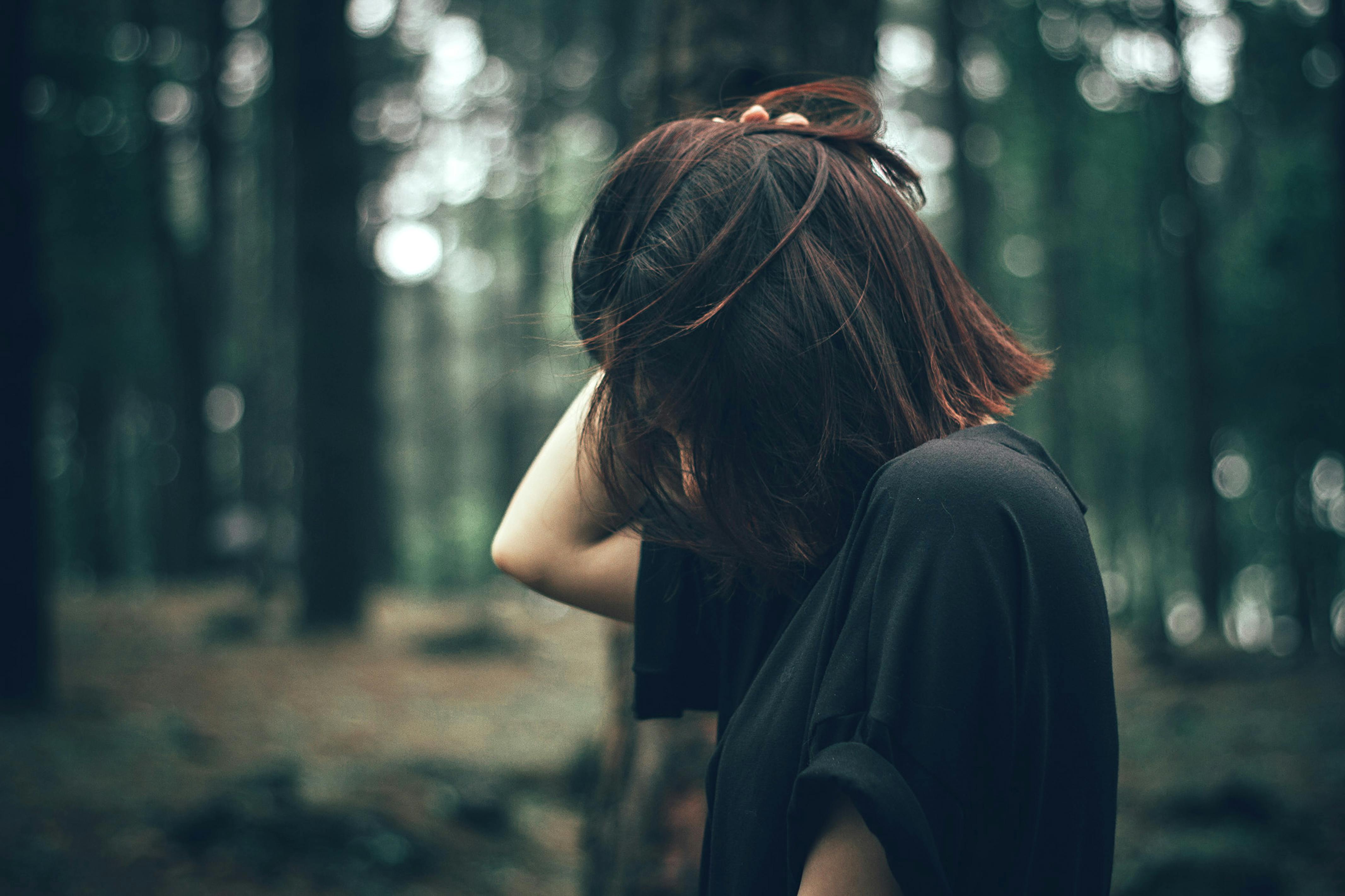 side view of woman wearing black shirt with her right hand on top of her hair