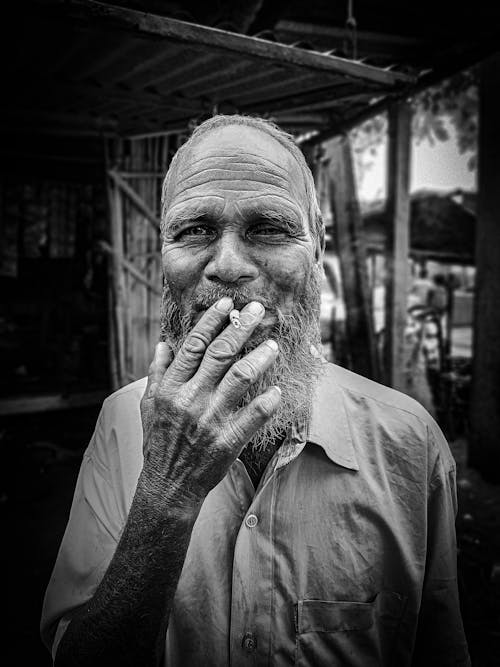 Grayscale Photo of Elderly Man Smoking Cigarette