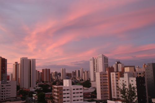 Free A city skyline with modern skyscrapers under a dramatic pink twilight sky. Stock Photo