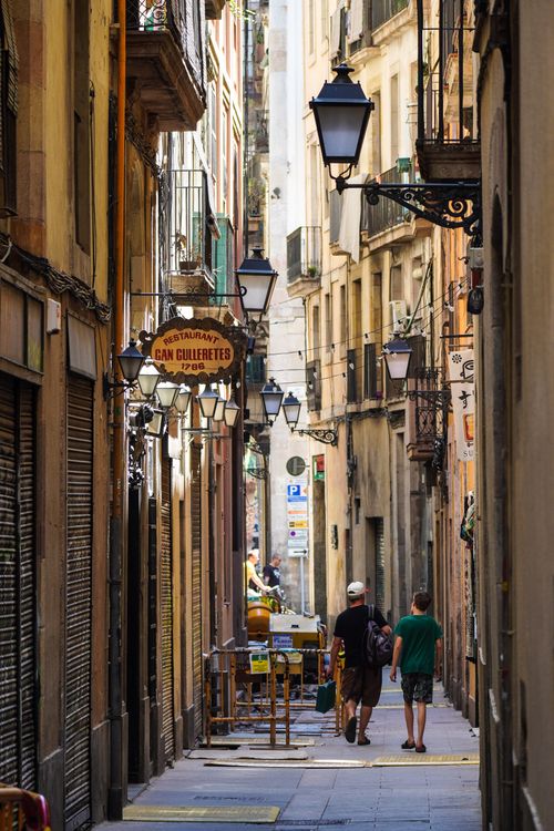 Free People strolling through a charming narrow alleyway in a vibrant Spanish city with rustic architecture. Stock Photo
