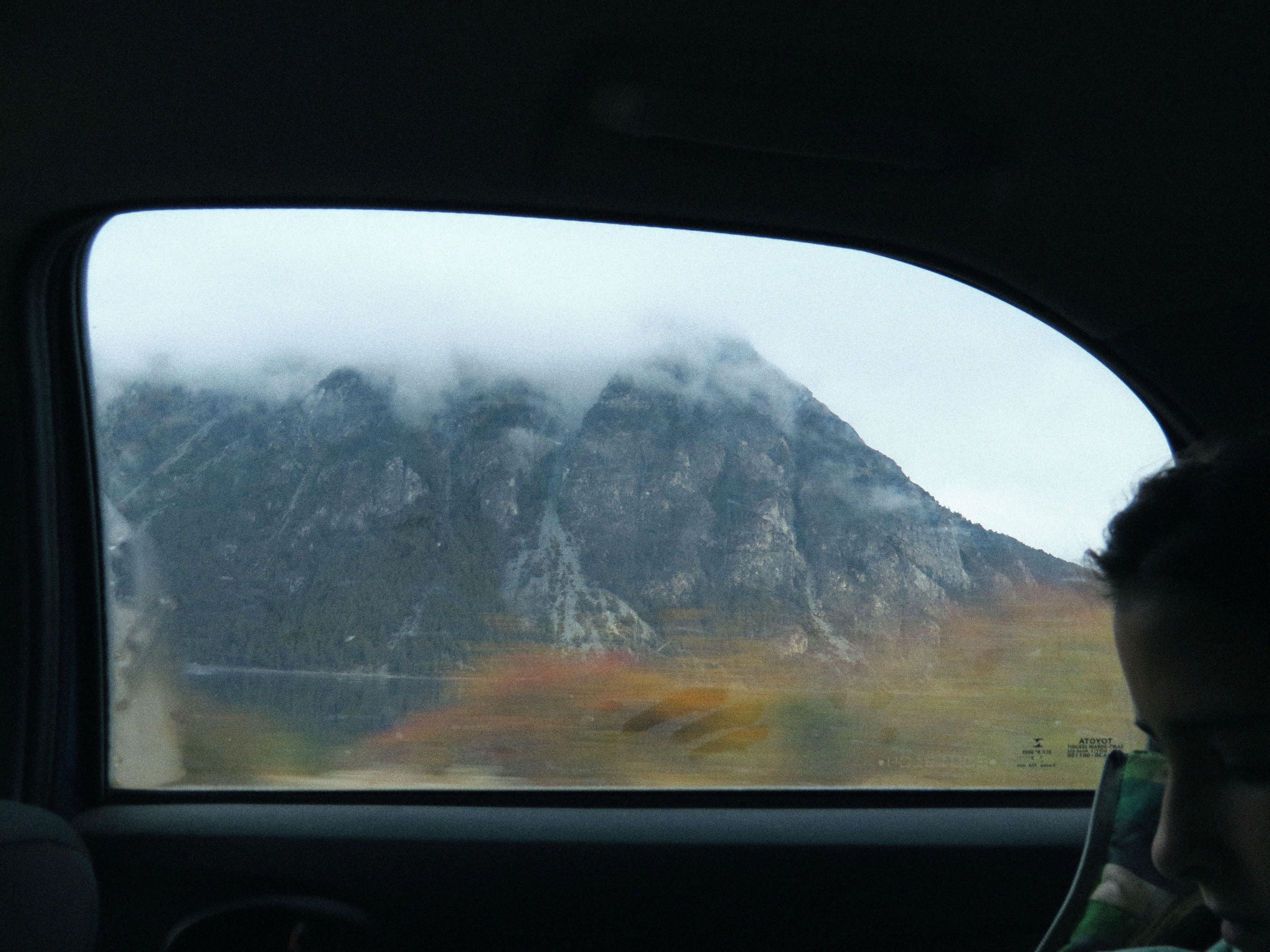 Foggy mountain landscape seen through a car window in Villa La Angostura, Argentina, capturing a serene travel moment.