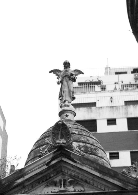 Black and white photo of an angel statue on a domed rooftop in Buenos Aires.