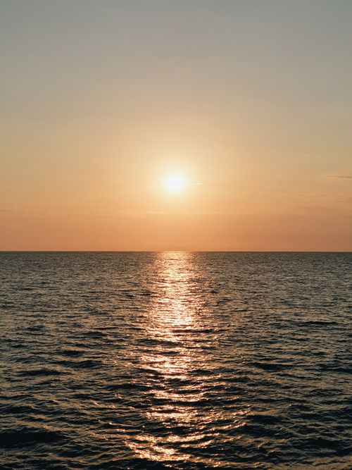 Free Peaceful ocean sunset casting golden reflections on the water surface. Stock Photo