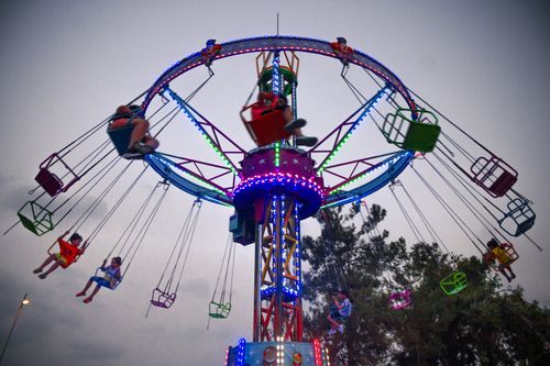 Free Vibrant carnival carousel with people enjoying a nighttime ride under colorful lights. Stock Photo