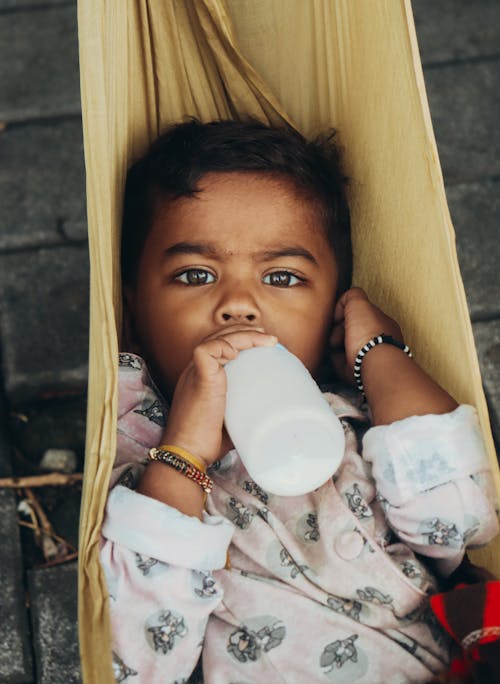 A Toddler Drinking Milk from a Baby Bottle