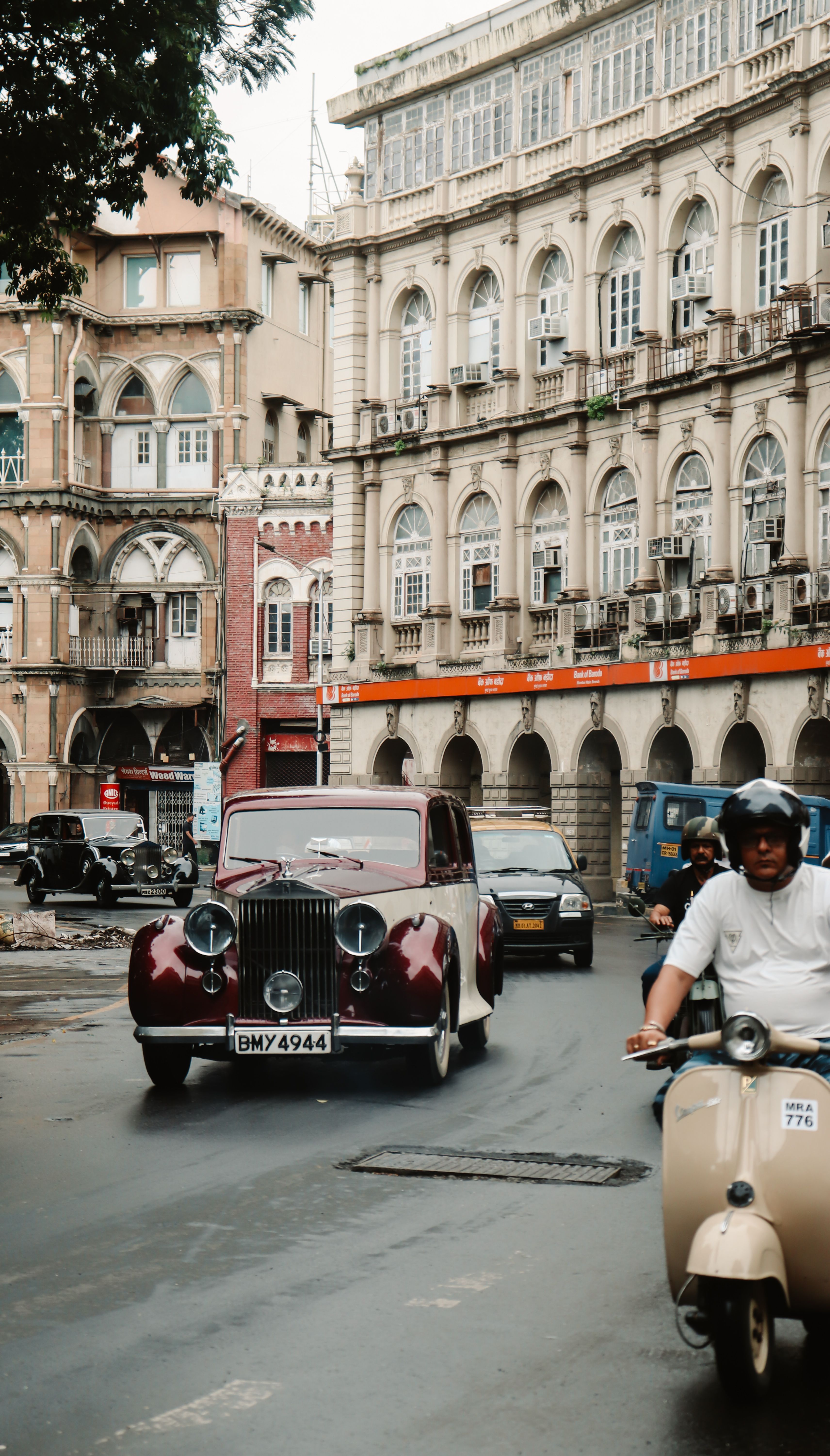 Classic vehicle driving through a bustling city street with historic architecture.