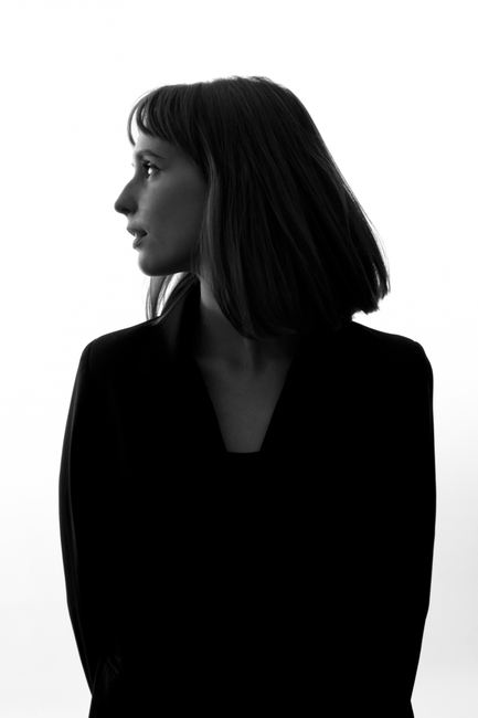 Artistic black and white silhouette of a woman in a blazer, gazing sideways.