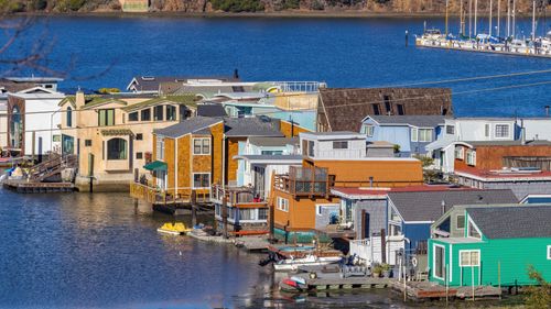Free A scenic view of vibrant floating houses docked along a clear blue waterfront. Stock Photo