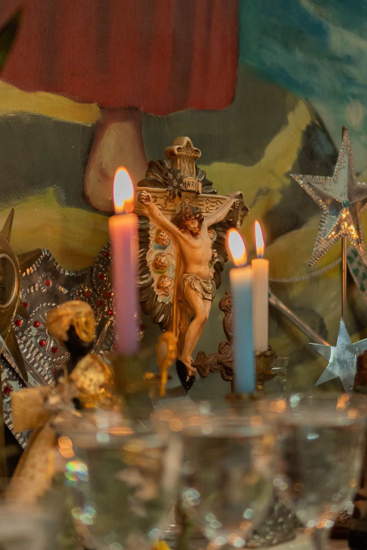 Sculpture Of Christ On Cross Among Lit Candles