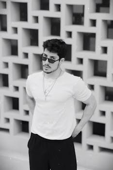 A stylish man in sunglasses poses against a unique geometric wall in Istanbul.