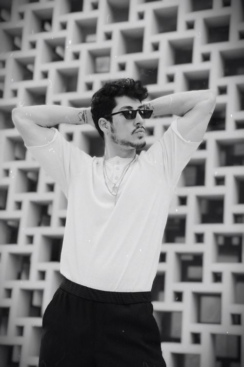Free Black and white portrait of a stylish man posing with sunglasses against a geometric background. Stock Photo