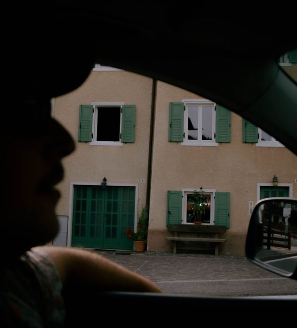 A unique view of Folgaria, Italy through a car window, capturing a building facade and silhouette.