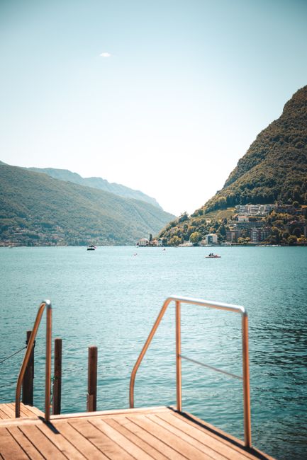 Experience tranquil lake views from a wooden pier in Lugano, Switzerland during summer.