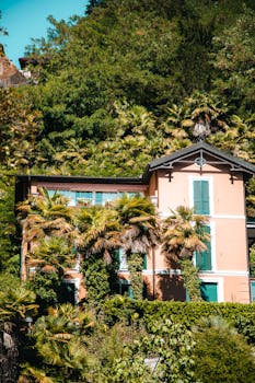 A beautiful villa nestled in lush greenery in Lugano, Switzerland, surrounded by palm trees and nature.