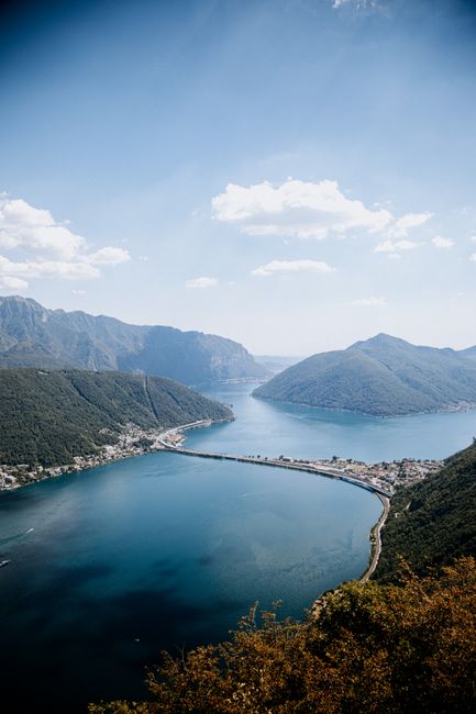 Stunning aerial view of Lake Lugano in Switzerland surrounded by mountains under a clear sky.