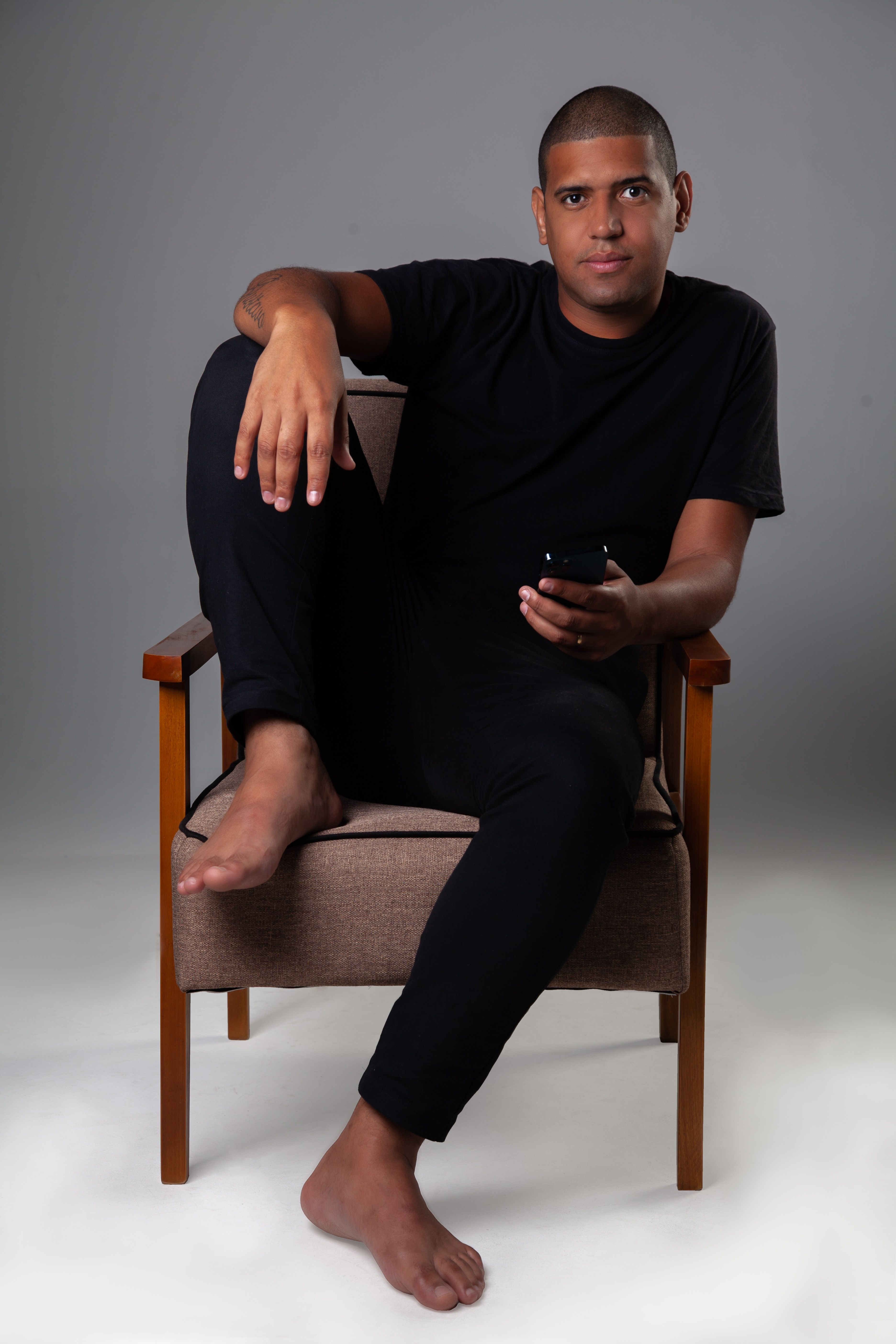 Casual young man in a black shirt sitting in armchair using smartphone.