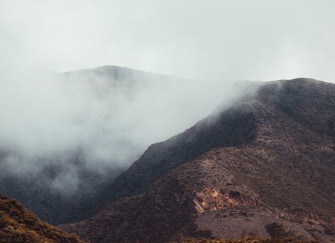 Misty mountain landscape with fog enveloping rugged peaks, creating a serene and mysterious atmosphere.