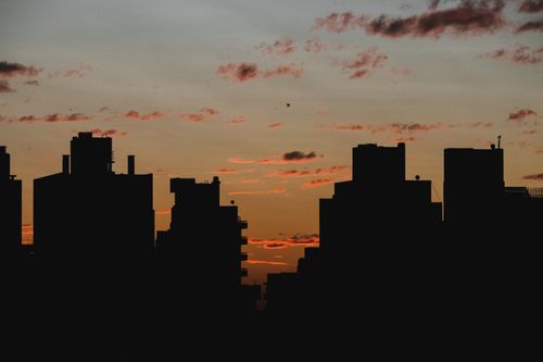Free A dramatic urban skyline silhouetted against a vibrant sunset sky. Stock Photo