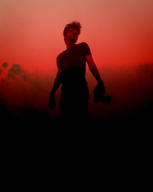 A striking silhouette of a man during a red-hued sunset, creating a dramatic backdrop.
