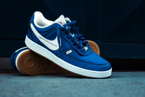 Free Close-up of blue sneakers on a concrete floor showcasing stylish design. Stock Photo