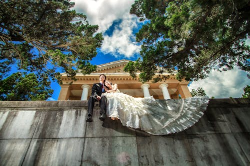 A Couple Sitting on Concrete Fence