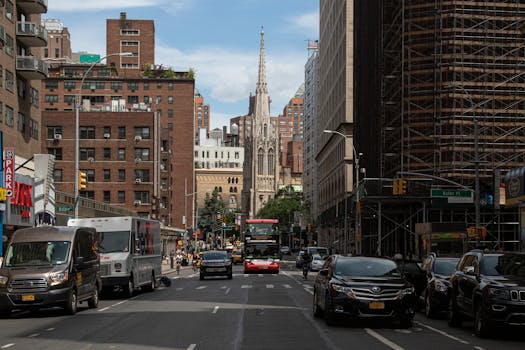 Vibrant cityscape of a New York street with traffic and historic church spire in the heart of downtown.