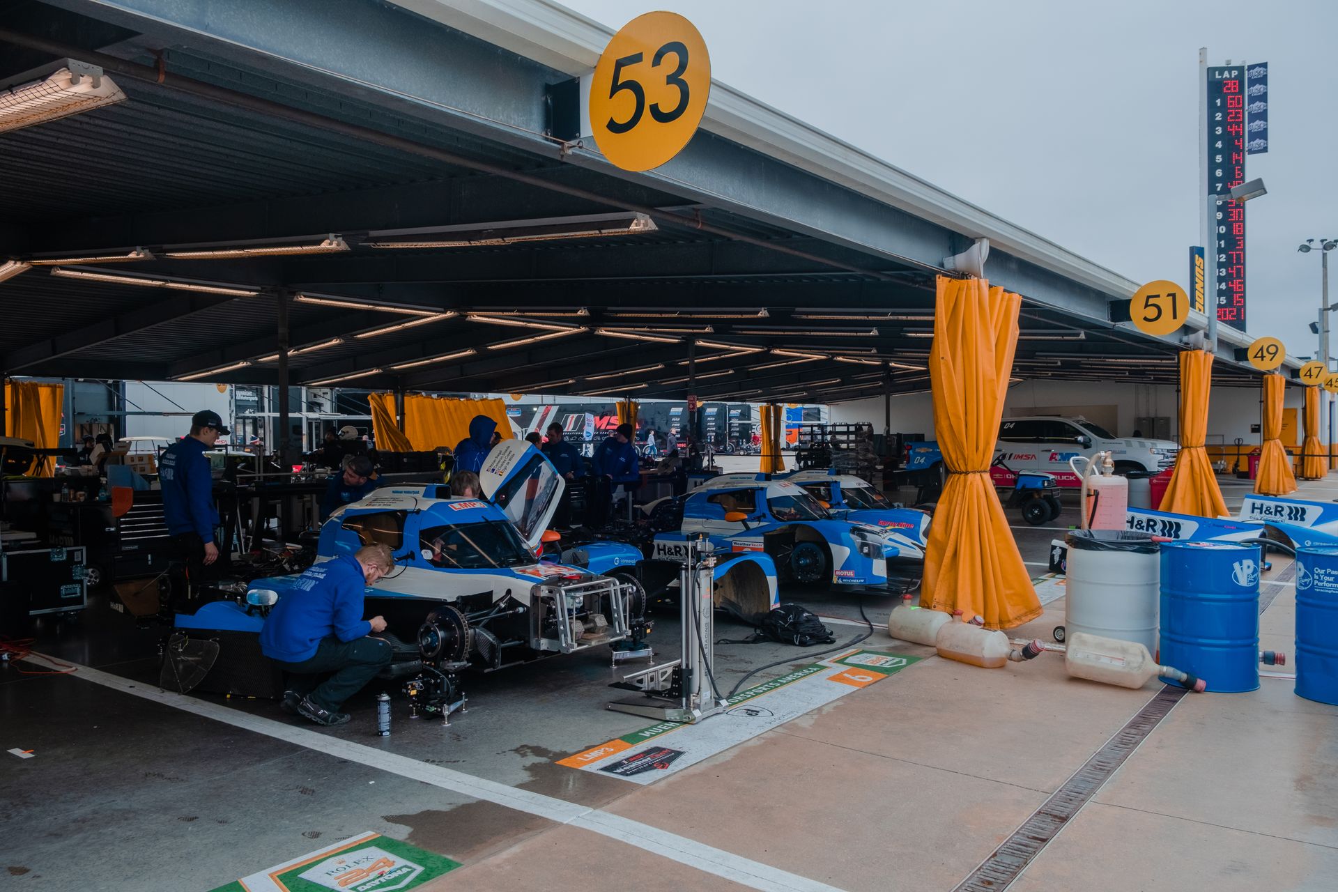 A team works on racing cars in a garage, showcasing motor sports preparation.