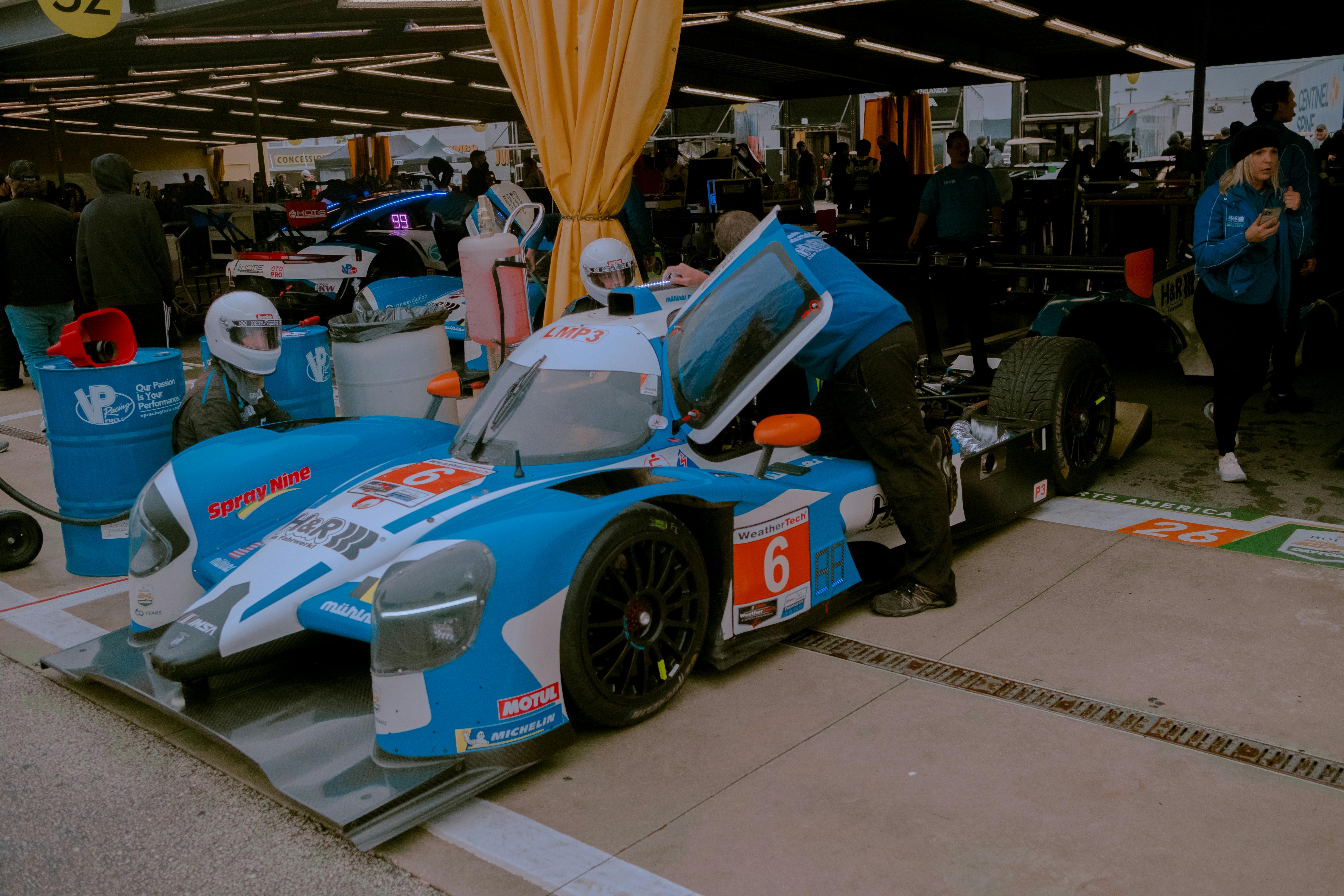 Mechanics work on a Ligier JS P217 racecar in a pit stop during a motorsport event.