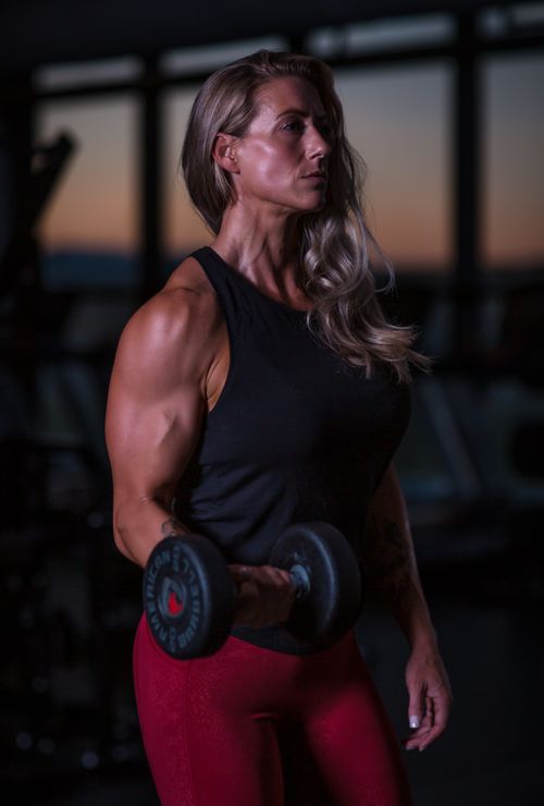 Free Woman lifting a dumbbell in gym setting, showcasing strength and fitness focus. Stock Photo