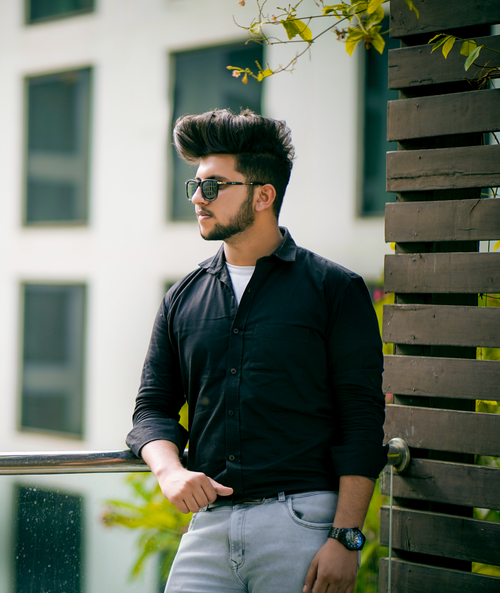 Free Contemporary portrait of a fashionable man in urban environment wearing sunglasses and black attire. Stock Photo