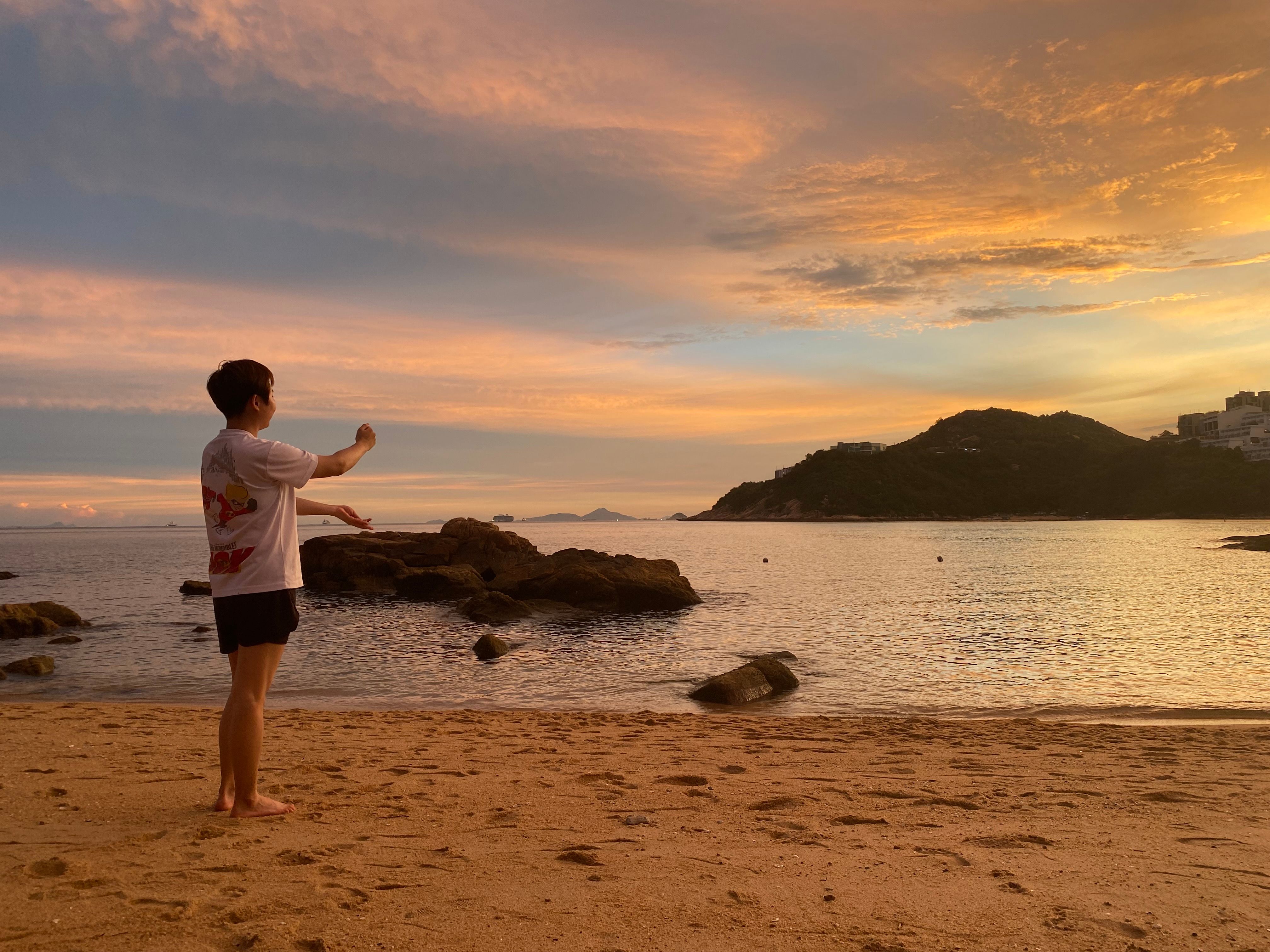 Serene beach scene with a person enjoying the sunset in Hong Kong.