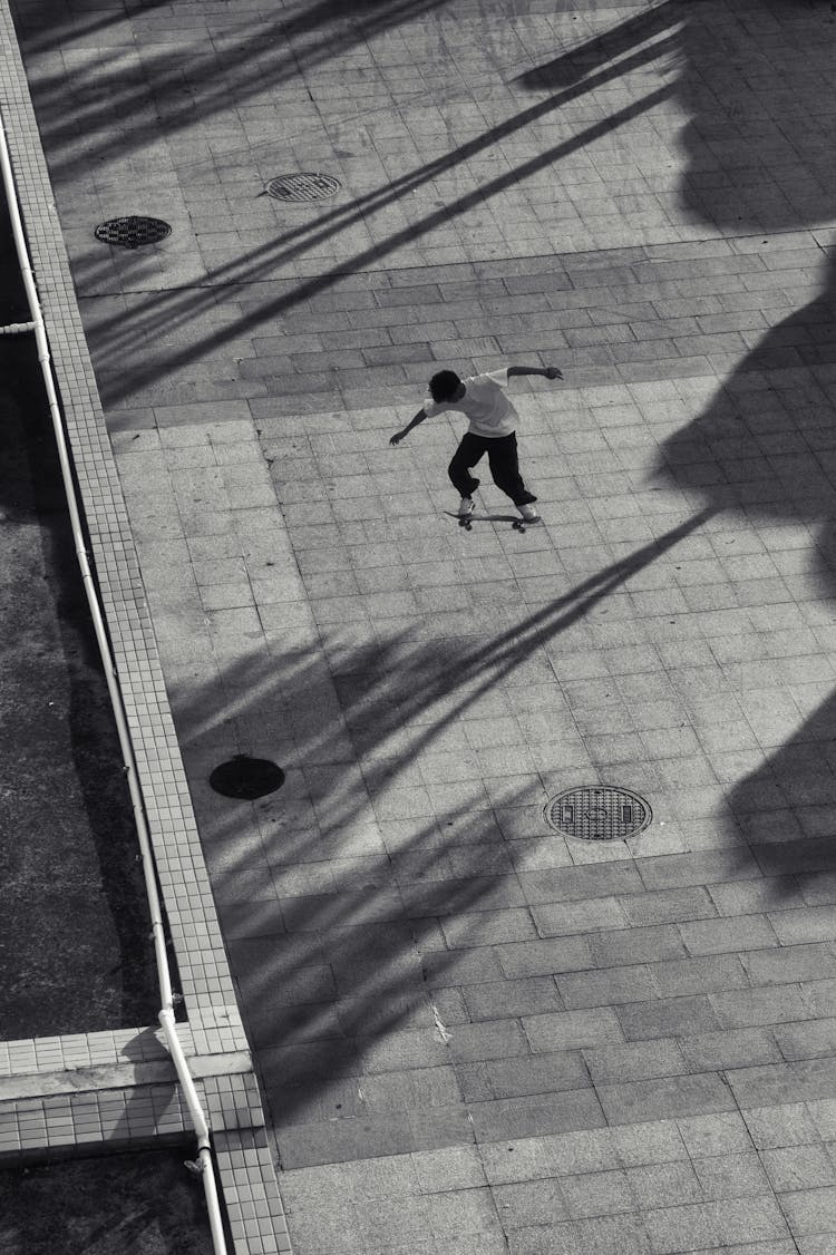 Skateboarder Doing Tricks On The Sidewalk In Black And White