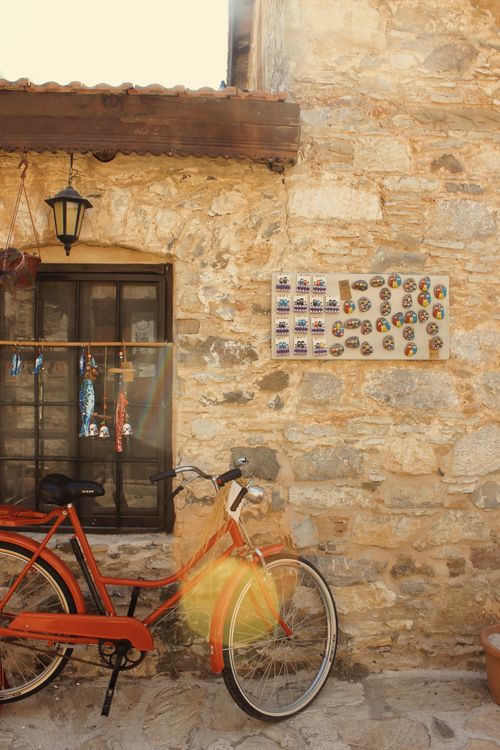 Free A vintage bicycle leaning against a rustic stone wall with hanging decor and a warm ambiance. Stock Photo
