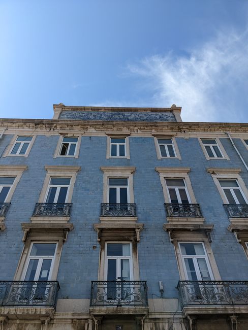 A low-angle view of a classic European building with a blue facade under a bright sky.