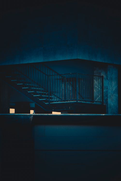 Free A dark and dramatic indoor staircase with metal railing, perfect for artistic moods. Stock Photo