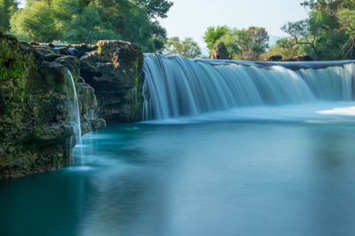Free A tranquil waterfall cascading gently in a lush, rocky setting, perfect for nature enthusiasts. Stock Photo
