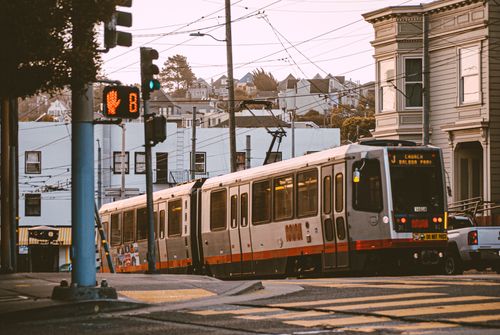 Free Tram navigating a street in San Francisco at sunset, capturing urban transportation and architecture. Stock Photo